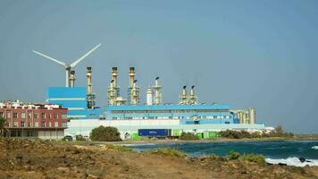 panorama de el línea costera con un planta y un viento turbina. video