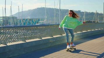 A girl rides a skateboard in front of a yacht club. video
