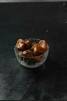 Bowl of dried dates isolated on black background photo