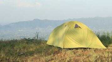 Camping tent on a hill with mountains in the background in the morning photo