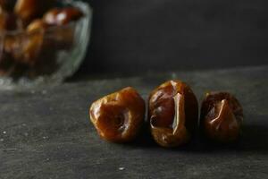 Bowl of dried dates isolated on black background photo