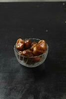 Bowl of dried dates isolated on black background photo