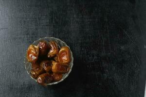 Bowl of dried dates isolated on black background photo