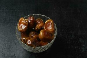 Bowl of dried dates isolated on black background photo