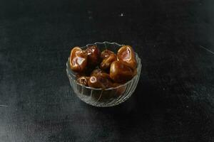 Bowl of dried dates isolated on black background photo
