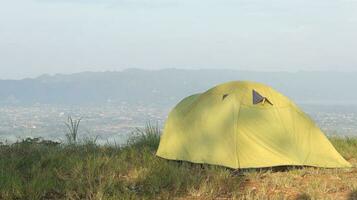 Camping tent on a hill with mountains in the background in the morning photo