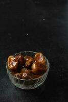 Bowl of dried dates isolated on black background photo