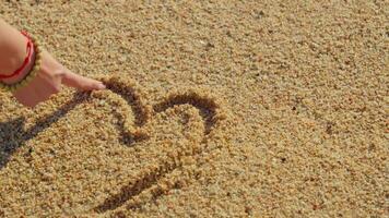 Hand draws heart on sand video