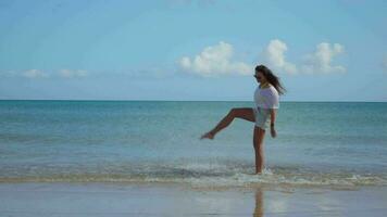 The girl raises the spray of water with her foot, blue sea. video