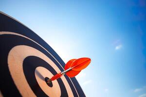 red darts arrows in the target center on blue sky background. Business target and success concept. photo