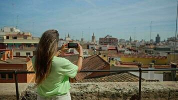 The girl takes pictures of the panorama of Valencia from the balcony video