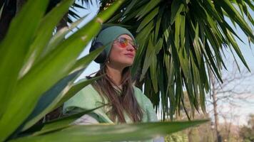 Girl in headphones among palm leaves video