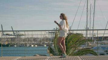 de meisje wandelingen langs de zee jachthaven, de wind klappen. video