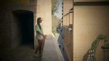 le fille regards de le balcon de le forteresse à le panorama de le rue. video