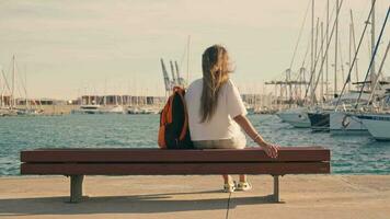 en turist flicka vilar på en bänk i en Yacht klubb. video