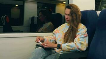 une femme en utilisant sa téléphone tandis que séance sur une train video