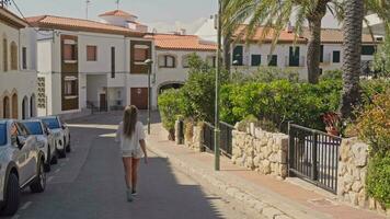 A woman strolling alongside parked cars on a scenic street in Terragona video