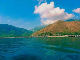 ver desde el mar a el montañas y el azul cielo con nubes foto