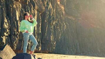 The girl stands against the background of a rock in the rays of the sun video