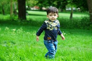 Cute Asian Pakistani Baby is Enjoying The Beautiful Sunny Day at Wardown Children and Public Park of Luton Town of England UK. Low Angle  Image Was Captured on April 03rd, 2023 photo