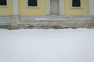 Snow and Building with Yellow Walls and Brown Base photo