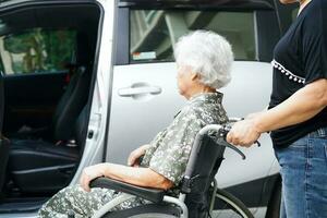 Caregiver help Asian elderly woman disability patient get in her car, medical concept. photo