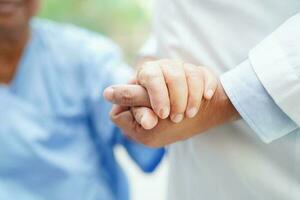 Doctor holding hands Asian elderly woman patient, help and care in hospital. photo