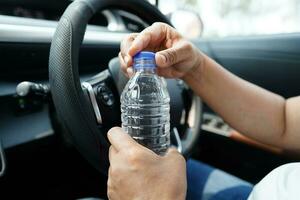 Asian woman driver hold drink in car, dangerous and risk an accident. photo