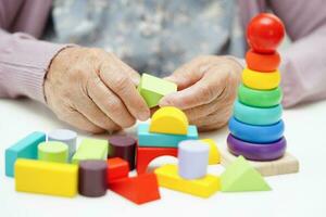 Asian elderly woman playing puzzles game to practice brain training for dementia prevention, Alzheimer disease. photo