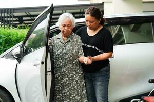 Caregiver help Asian elderly woman disability patient get in her car, medical concept. photo