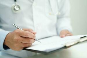 Doctor checking and note diagnosis medicine in clipboard of patients in hospital. photo