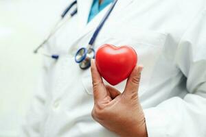 Asian woman doctor holding red heart for health in hospital. photo