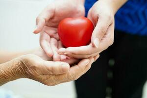 Asian young boy give red heart to old grandmother with love and care. photo