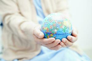 Bangkok, Thailand April 1, 2023 Asian elderly woman patient holding globe in hand at hospital. photo