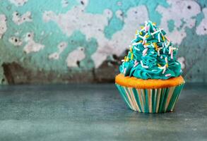 Cupcake decorated with blue icing and sprinkles photo