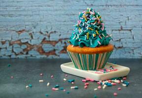 Cupcake decorated with blue icing and sprinkles photo