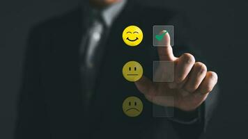a businessman touching the virtual screen on the happy smile face icon to give satisfaction in service.rating very impressed.Customer service and Satisfaction concept photo
