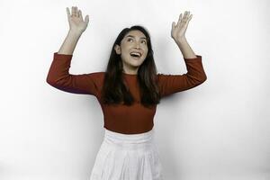 Excited Asian woman wearing red t-shirt, pointing at the copy space on top of her, isolated by white background photo