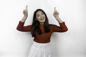 Excited Asian woman wearing red t-shirt, pointing at the copy space on top of her, isolated by white background photo