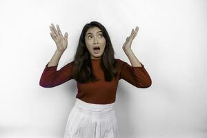 Shocked Asian woman wearing red t-shirt, pointing at the copy space above her, isolated by white background photo