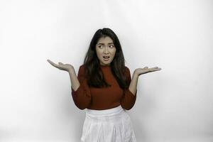 A thoughtful young Asian woman is wearing red t-shirt looks confused between choices, isolated by white background photo