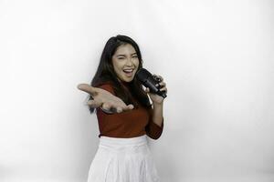 retrato de una mujer asiática despreocupada, divirtiéndose en el karaoke, cantando en el micrófono mientras está de pie sobre fondo blanco foto