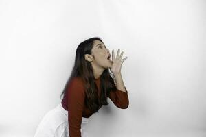 Young beautiful woman wearing a red top shouting and screaming loud with a hand on her mouth. communication concept. photo