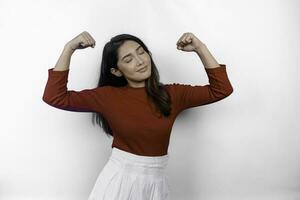 Excited Asian woman wearing a red top showing strong gesture by lifting her arms and muscles smiling proudly photo