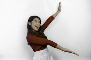 Excited Asian woman wearing red t-shirt, pointing at the copy space beside her, isolated by white background photo