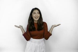 Excited Asian woman wearing red t-shirt, pointing at the copy space beside her, isolated by white background photo