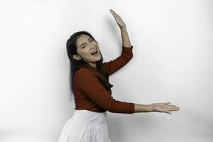 Excited Asian woman wearing red t-shirt, pointing at the copy space beside her, isolated by white background photo