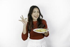 Image of smiling young Asian girl holding a plate of french fries and gesturing OK sign, isolated on white background photo