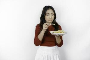 Young disgusted woman in casual sweater is holding fast food french fries potato with disgusted gesture isolated on white background. People lifestyle food concept. photo