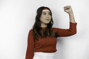 A young Asian woman with a happy successful expression wearing red top and flag headband isolated by white background. Indonesia's independence day concept. photo